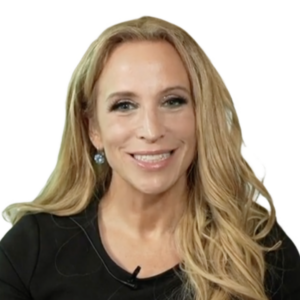 A woman with long blonde hair, wearing a black top and earrings, smiles at the camera against a plain white background, ready to discuss the evolving cybersecurity landscape.